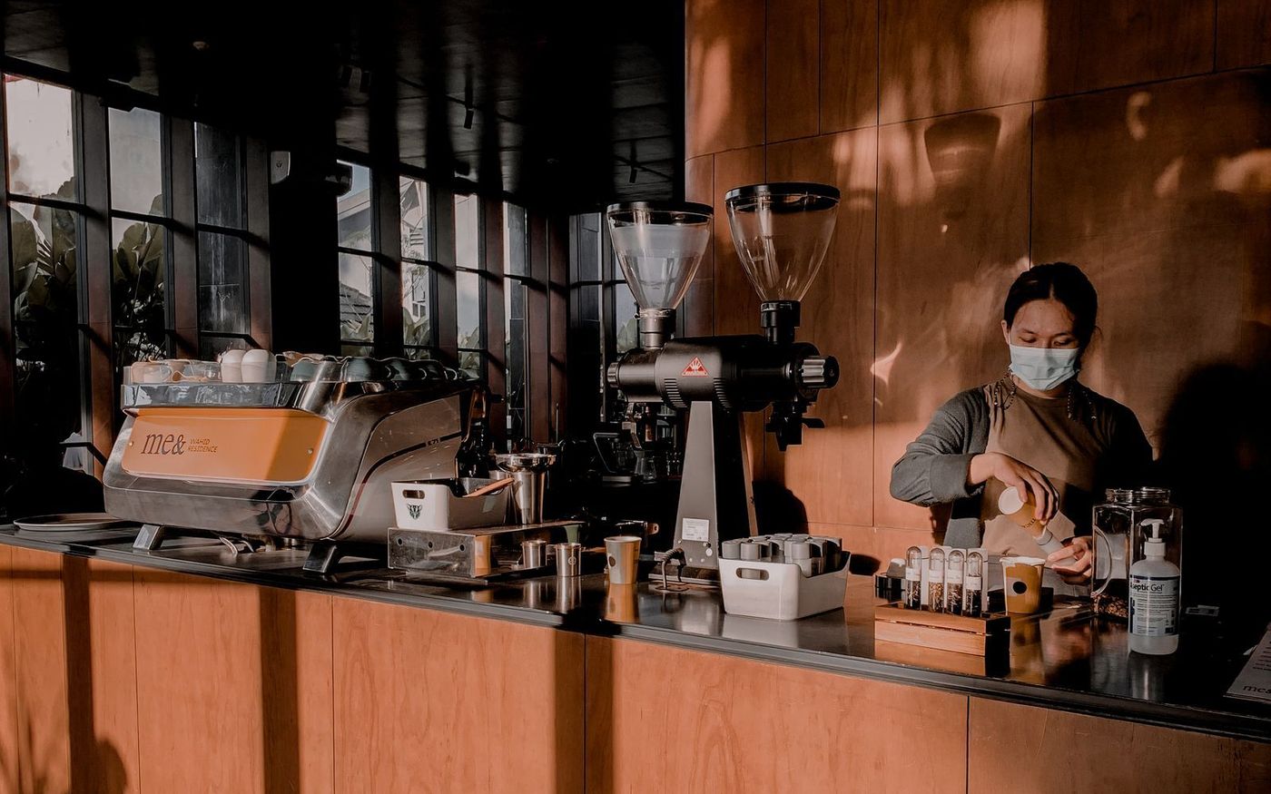A barista preparing coffee at a warm copper-toned café counter