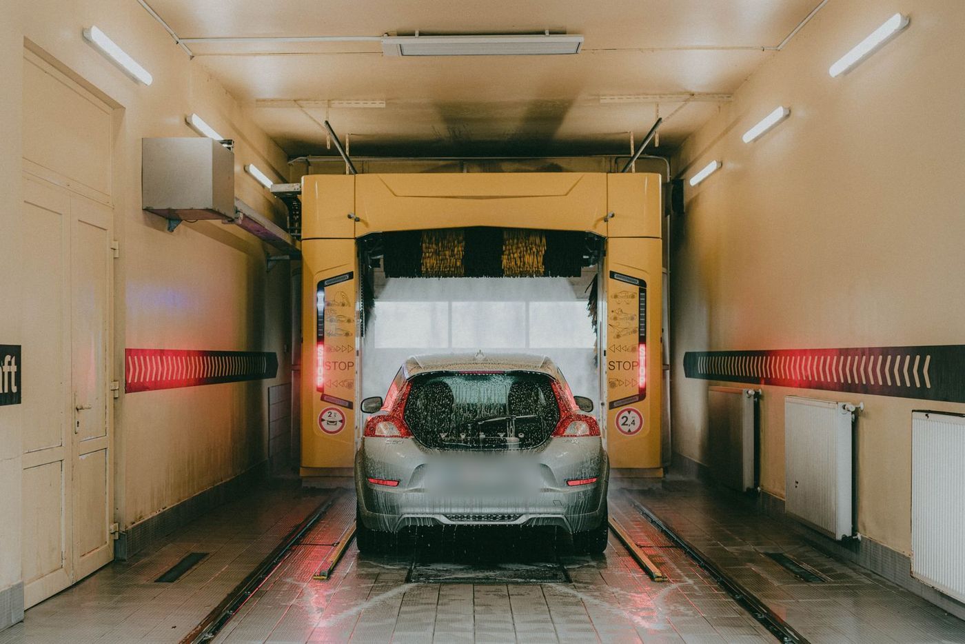 A car inside an automatic car-wash tunnel under warm lights